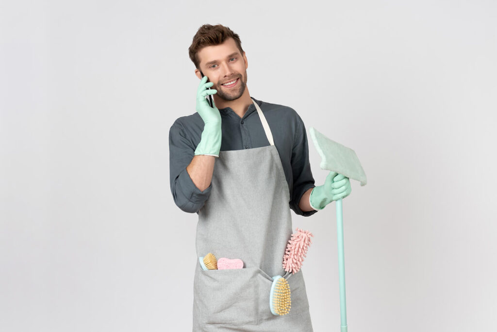 A man who stands with cleaning equipment and talk to phone
